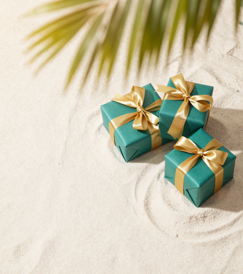 Wrapped gifts with teal and gold ribbon on the beach